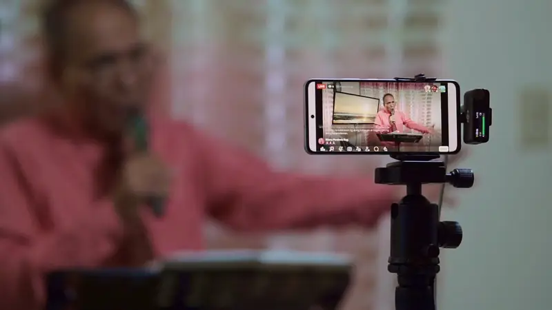 A phone on a tripod filming a preacher